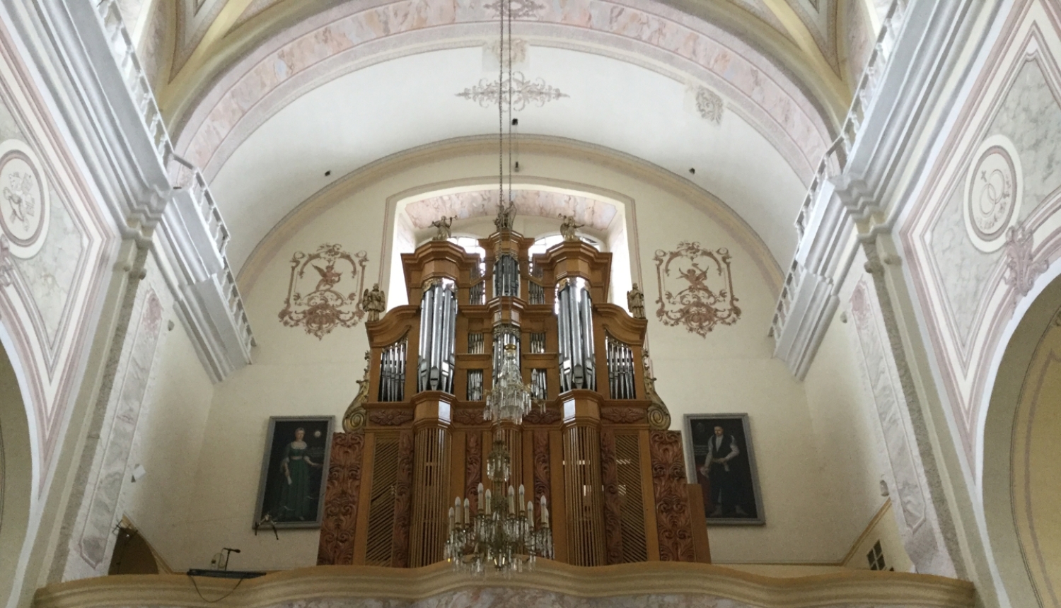 Ērģeļu prospekts saktā no apakšas uz augšu. Fonā gaišs, majestātisks baznīcas interjers.