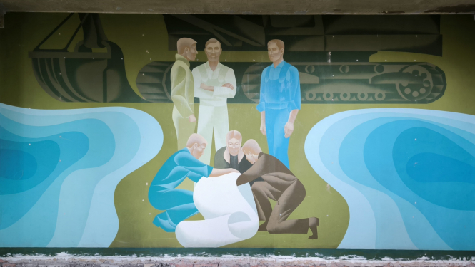 Zaļi zilos, gaiši spilgtos toņos veidota aina, kuras priekšplānā cilvēku grupa pēta papīra dokumentu, bet aiz viņiem stāv vēl trīs cilvēki. Aizmugurē redzama meliorācijas tehnika, bet sānos ūdens.