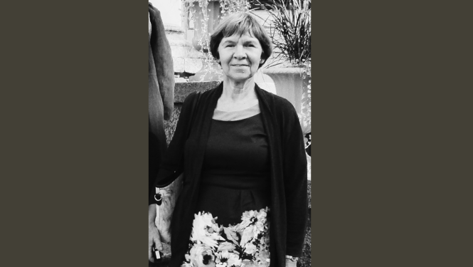 Melnbalts attēls ar pelēkām malām, tajā redzama smaidoša sieviete vecumā virs 50, tērpusies svārkos, krekliņā un jakā. Mati īsi apgriezti.