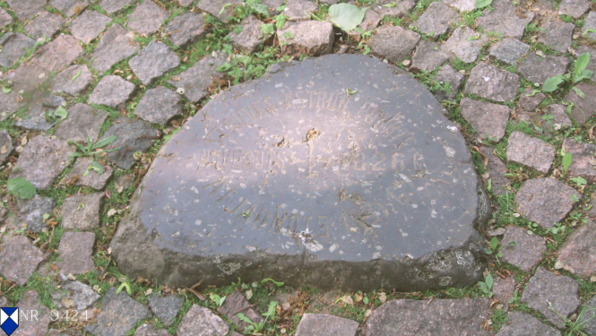 Melns akmens piemineklis ar uzrakstiem un diviem metāla cilņiem, kas atzīmē Strūves ģeodēziskā loka Jēkabpils astronomisko novērojumu punktu. Piemineklis atrodas akmens bruģī, apkārt saaugusi zāle.