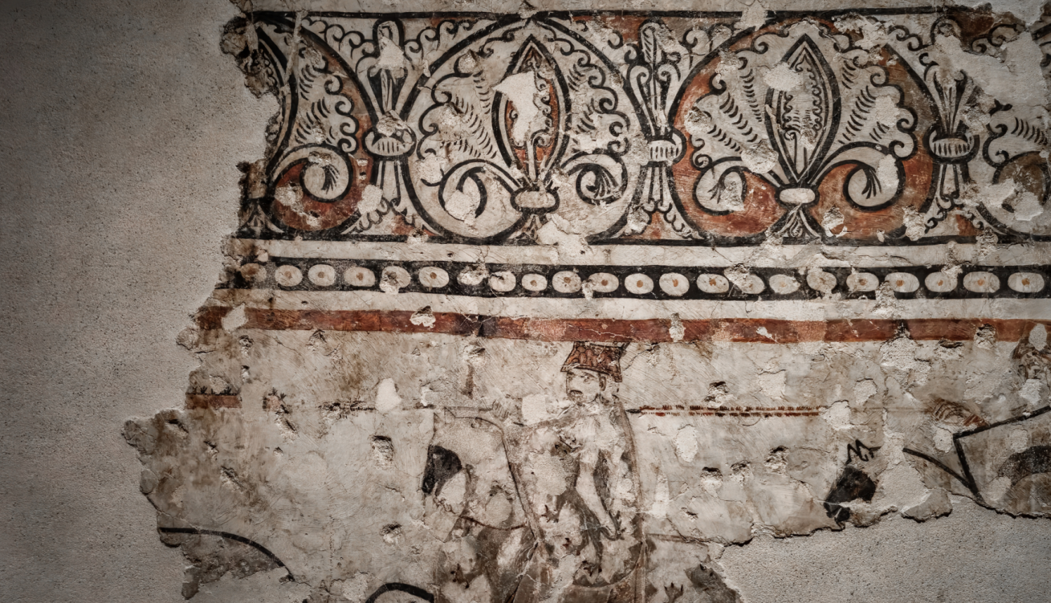 Daļēji saglabājies sienas gleznojums ar ģeometriskiem un augu ornamentiem. Gleznojums ir izbalējis un bojāts, atklājot sienas virsmu. augšpusē, zem tā ir horizontāla līnija ar punktveida elementiem.