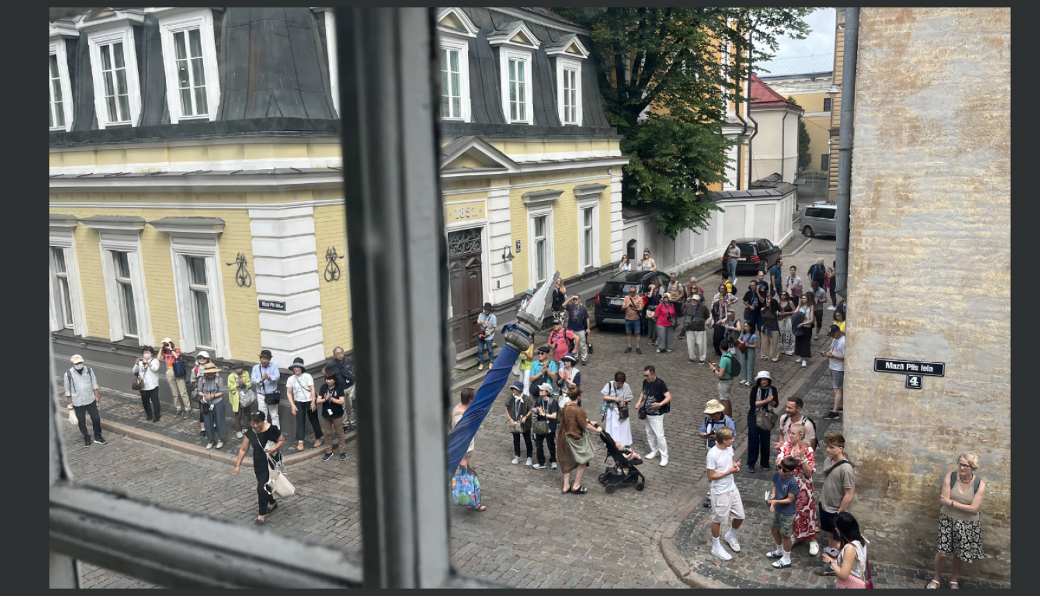 Rakstu ilustrējošs attēls ar tūristu pūli Vecrīgā. Aina uzņemta no Nacionālās kultūras mantojuma pārvaldes loga otrajā stāvā.