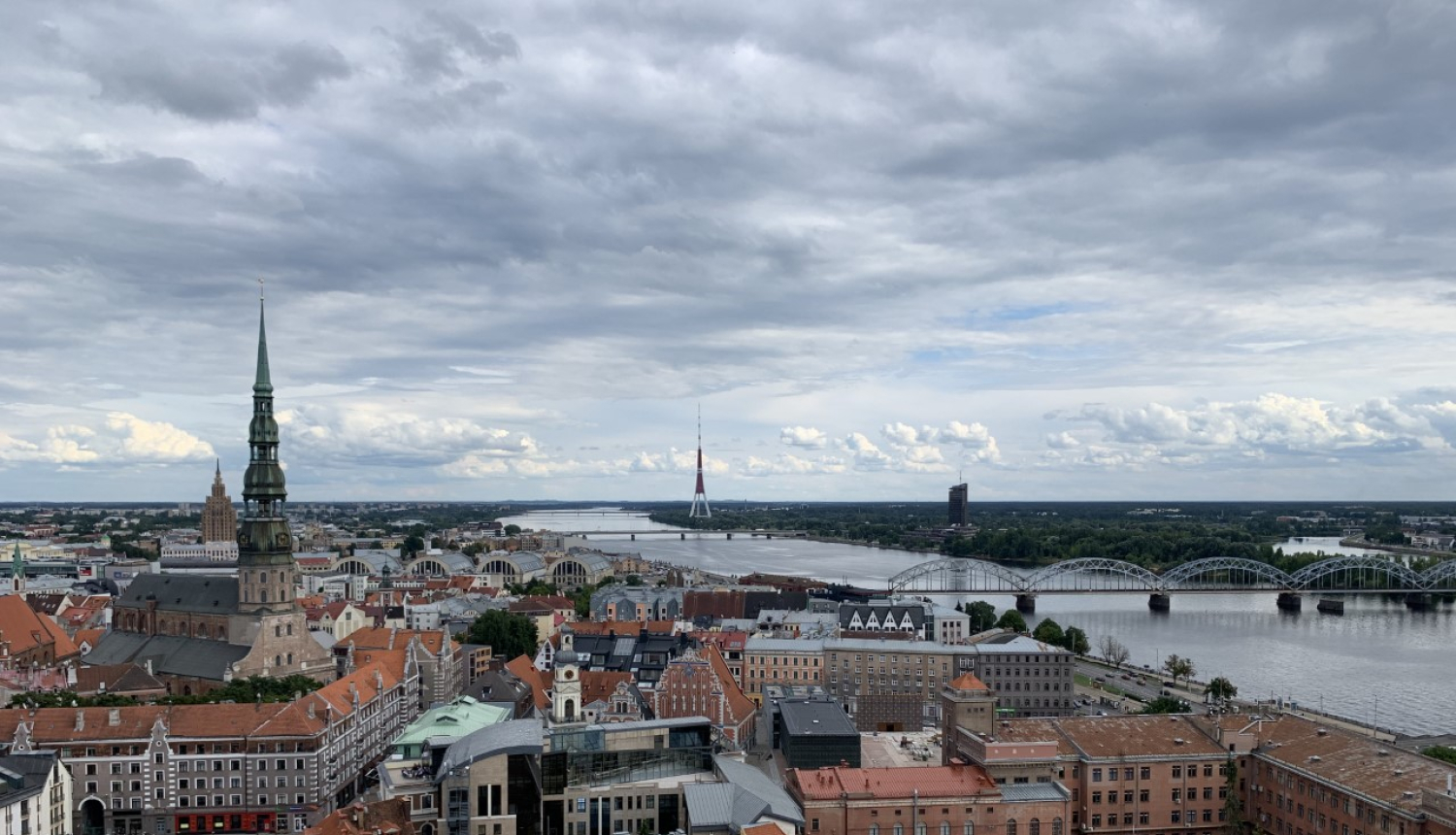 Attēlā redzams no gaisa uzņemts skats ar Rīgas vēsturiskā centra sirdi - Vecrīgu. Tajā redzami arī Vecrīgas kvartāli starp Kaļķu un Tirgoņu ielām, par kuru potenciālo apbūvi vēstī raksts. Attēlā redzama arī Daugava un dinamiskas debesis ar mākoņiem, bet tālumā paceļas Pētera baznīcas smaile.