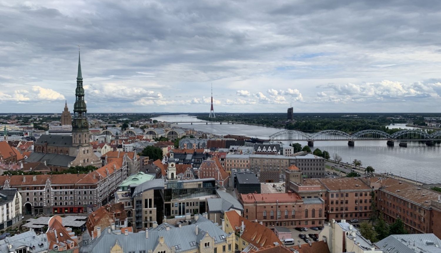 Attēlā redzams no gaisa uzņemts skats ar Rīgas vēsturiskā centra sirdi - Vecrīgu. Tajā redzami arī Vecrīgas kvartāli starp Kaļķu un Tirgoņu ielām, par kuru potenciālo apbūvi vēstī raksts. Attēlā redzama arī Daugava un dinamiskas debesis ar mākoņiem, bet tālumā paceļas Pētera baznīcas smaile.